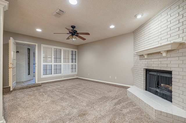 unfurnished living room with carpet flooring, ceiling fan, a textured ceiling, and a brick fireplace