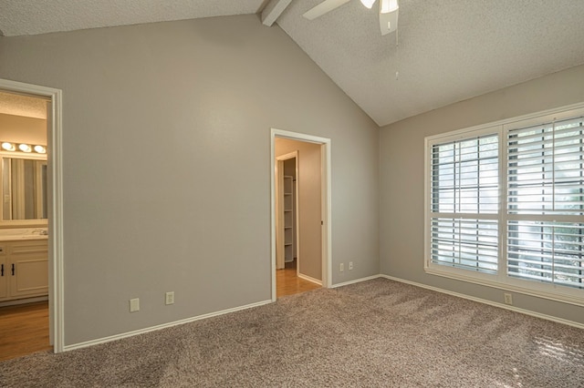 unfurnished bedroom featuring connected bathroom, light carpet, ceiling fan, and vaulted ceiling with beams