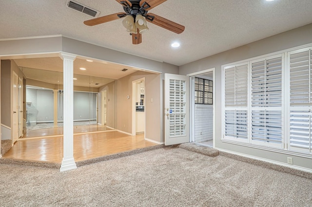 interior space with decorative columns, ceiling fan, and a textured ceiling