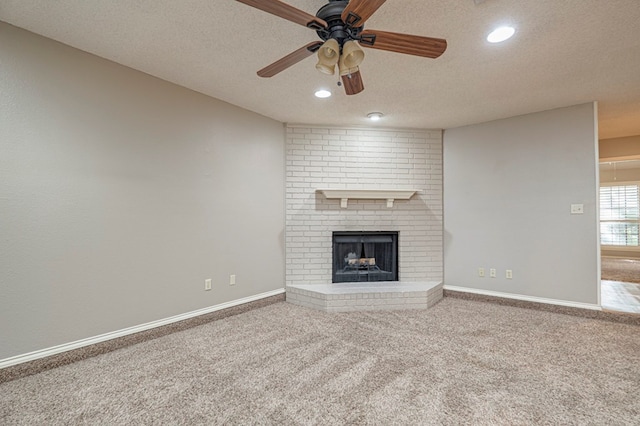 unfurnished living room with ceiling fan, a fireplace, carpet floors, and a textured ceiling