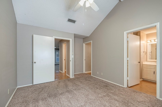 unfurnished bedroom with a textured ceiling, light carpet, ceiling fan, and vaulted ceiling