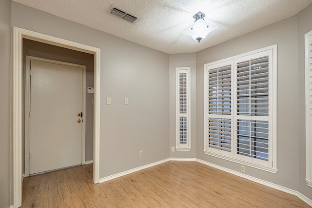 spare room featuring light hardwood / wood-style flooring and a textured ceiling