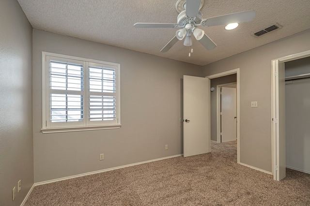 unfurnished bedroom featuring carpet, a textured ceiling, a closet, and ceiling fan