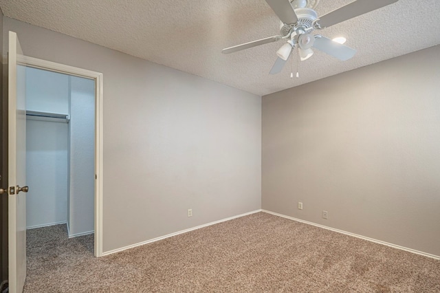 unfurnished bedroom with carpet, a textured ceiling, ceiling fan, a spacious closet, and a closet