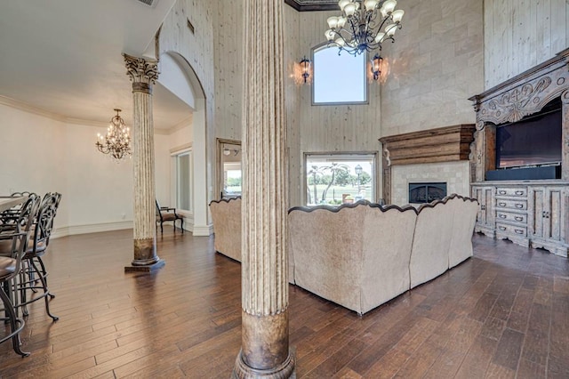 living room with a high ceiling, an inviting chandelier, dark wood-style floors, and a fireplace