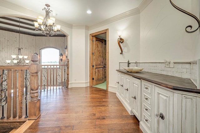 interior space with crown molding, an inviting chandelier, a sink, and hardwood / wood-style floors