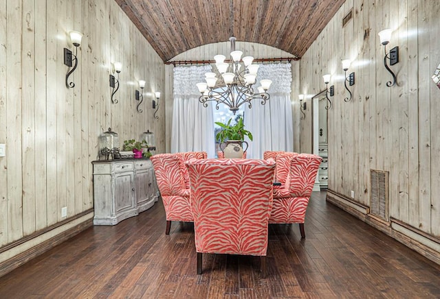 dining space with visible vents, wood walls, dark wood-style flooring, a notable chandelier, and vaulted ceiling
