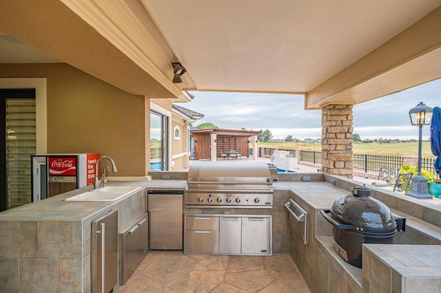 view of patio featuring exterior kitchen, a sink, a grill, and fence