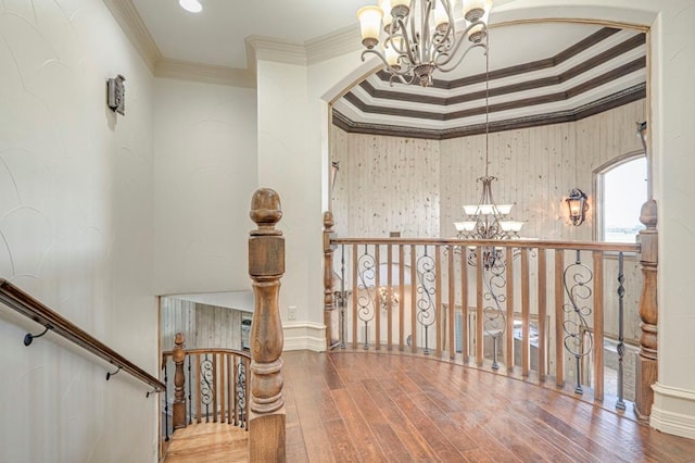 hallway with ornamental molding, wood finished floors, and a chandelier