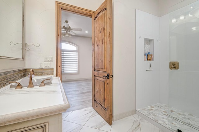 full bathroom featuring ceiling fan, a shower with shower door, vanity, baseboards, and marble finish floor