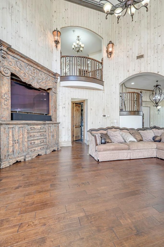 living area featuring wood finished floors, wooden walls, a high ceiling, and a notable chandelier