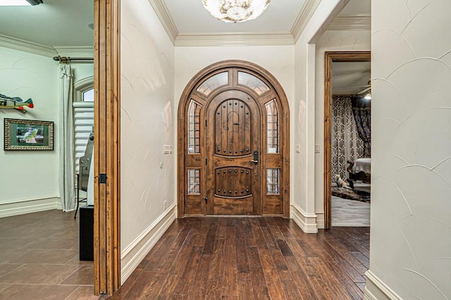 foyer featuring crown molding, arched walkways, baseboards, and hardwood / wood-style floors