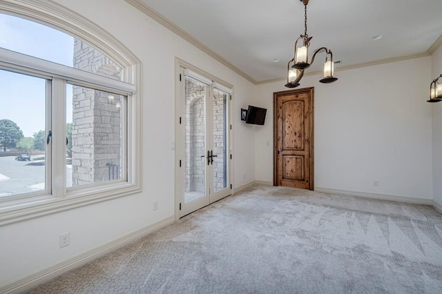 spare room featuring carpet floors, ornamental molding, baseboards, and an inviting chandelier