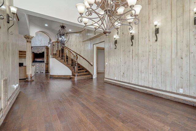interior space featuring an inviting chandelier, stairs, wooden walls, and hardwood / wood-style floors