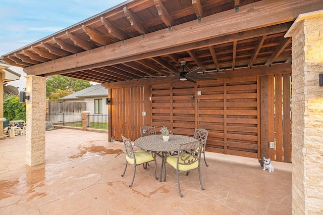view of patio with outdoor dining area, a ceiling fan, and fence