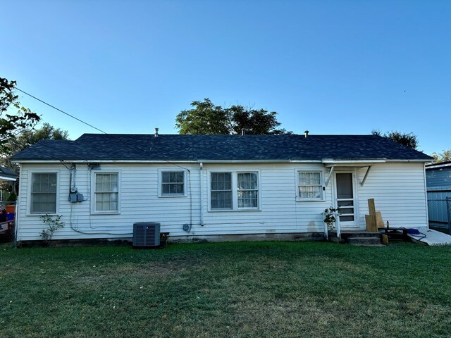 rear view of house featuring cooling unit and a yard