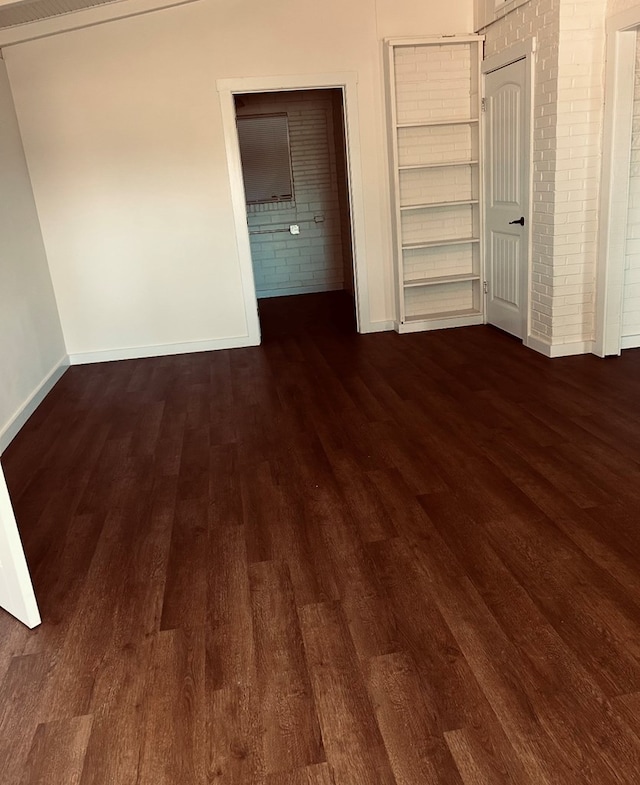 126 Coliseum Dr, Snyder, TX 79549 - unfurnished bedroom with brick wall, baseboards, and wood finished floors
