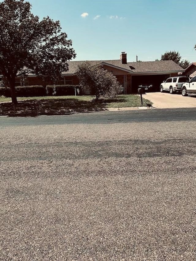 view of front of home featuring a garage, driveway, and a chimney