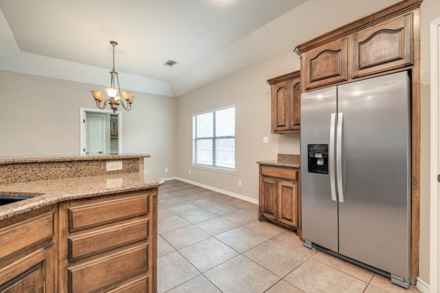 kitchen with pendant lighting, light tile patterned flooring, an inviting chandelier, light stone countertops, and stainless steel fridge