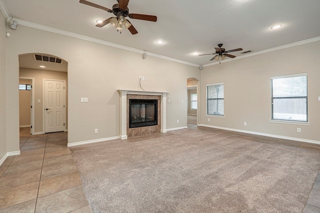 unfurnished living room with ceiling fan, a healthy amount of sunlight, a fireplace, and crown molding