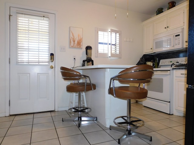 kitchen featuring light tile patterned floors, white appliances, and white cabinetry