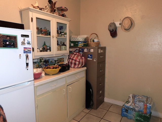 kitchen with white fridge, light tile patterned floors, and white cabinetry