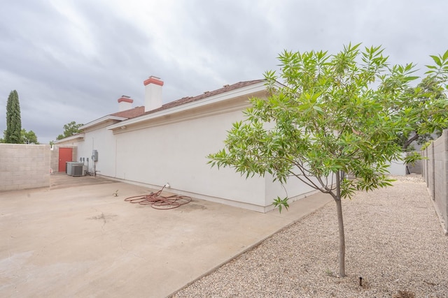 view of property exterior with central air condition unit and a patio