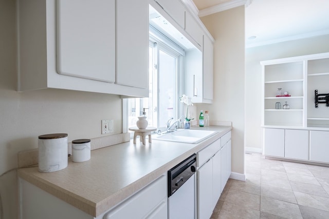 kitchen featuring ornamental molding, dishwashing machine, sink, light tile patterned floors, and white cabinetry