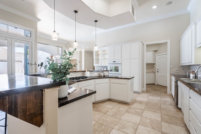 kitchen with white cabinets, appliances with stainless steel finishes, backsplash, and hanging light fixtures