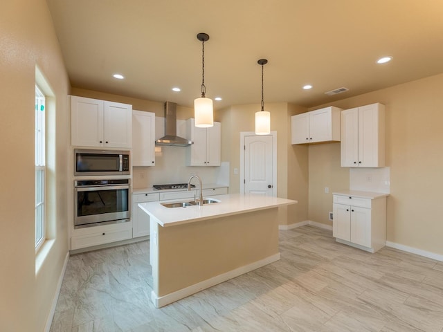 kitchen with stainless steel appliances, visible vents, white cabinetry, a sink, and wall chimney exhaust hood