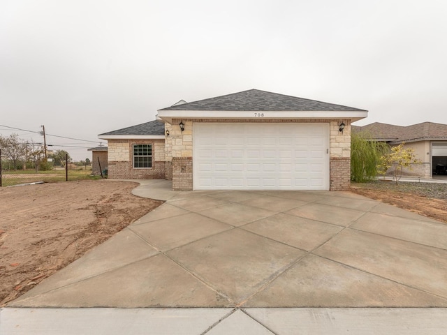 view of front facade with stone siding, concrete driveway, roof with shingles, and an attached garage