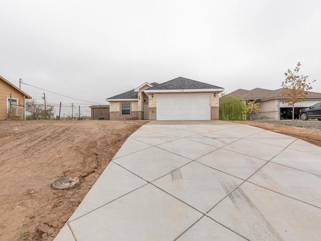 view of front of property featuring driveway, an attached garage, a shingled roof, and brick siding