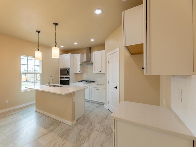 kitchen with tasteful backsplash, wall chimney exhaust hood, appliances with stainless steel finishes, white cabinetry, and a sink