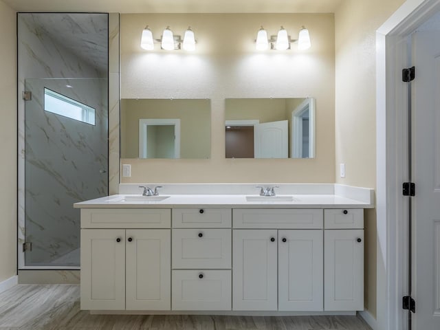 full bathroom featuring double vanity, a sink, and a marble finish shower