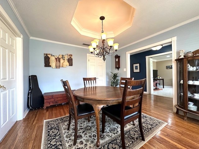 3320 Lancewood Ln, Odessa, TX 79762 - dining space featuring a chandelier, dark wood-style flooring, crown molding, and a tray ceiling