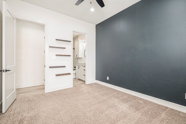 unfurnished bedroom with ensuite bathroom, light carpet, and ceiling fan