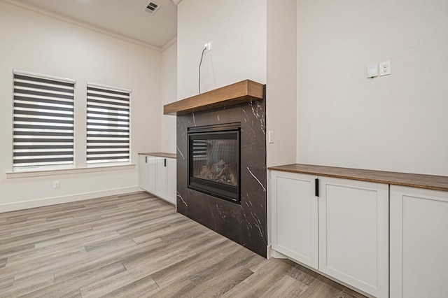 unfurnished living room with ornamental molding and light wood-type flooring