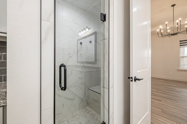 bathroom featuring hardwood / wood-style floors, a notable chandelier, and walk in shower