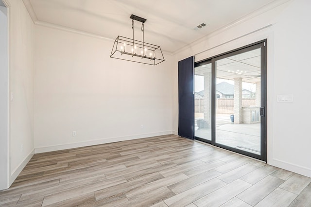 empty room featuring crown molding, a notable chandelier, and light wood-type flooring