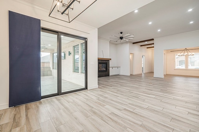 unfurnished living room with ceiling fan with notable chandelier and light wood-type flooring