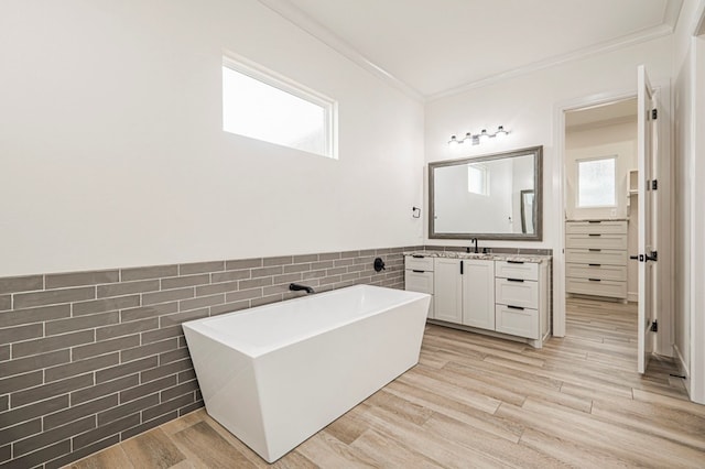 bathroom featuring hardwood / wood-style flooring, ornamental molding, a bath, and tile walls