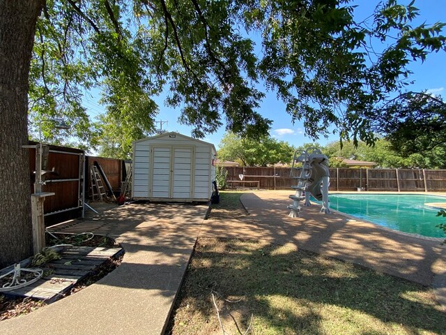 view of yard featuring a fenced in pool and a storage shed