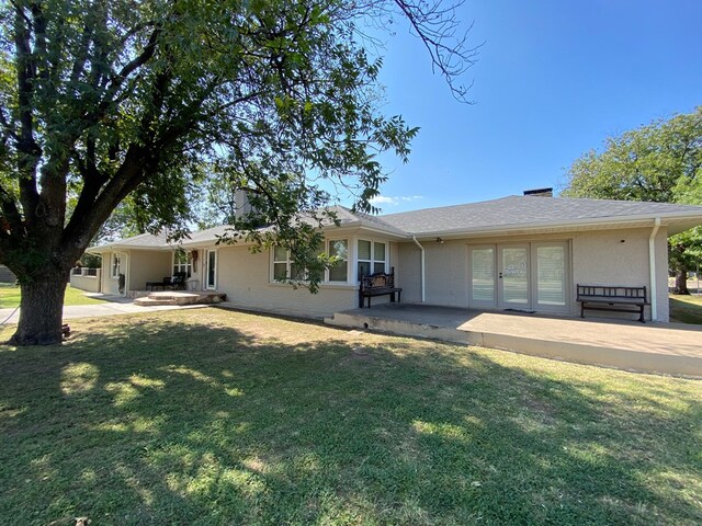 rear view of property with a lawn, a patio area, and french doors