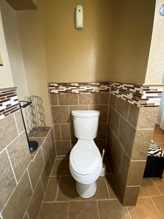 bathroom with toilet and tile walls