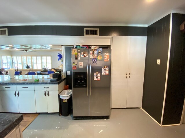 kitchen with dark stone counters, ceiling fan, stainless steel fridge, ornamental molding, and white cabinetry