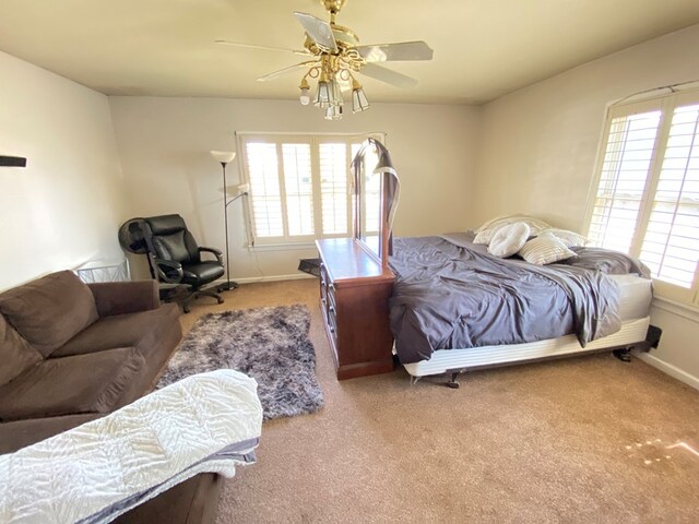 bedroom featuring ceiling fan, light carpet, and multiple windows