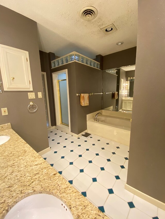 bathroom with vanity, a textured ceiling, and shower with separate bathtub