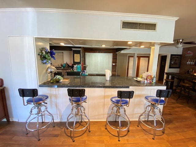 kitchen with kitchen peninsula, crown molding, ceiling fan, and hardwood / wood-style flooring