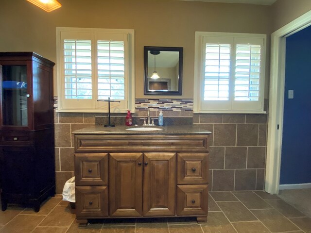 bathroom featuring vanity, a healthy amount of sunlight, and tile walls