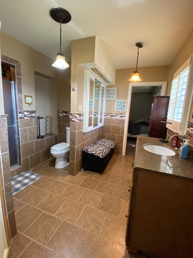 bathroom featuring tile patterned flooring, vanity, toilet, and tile walls